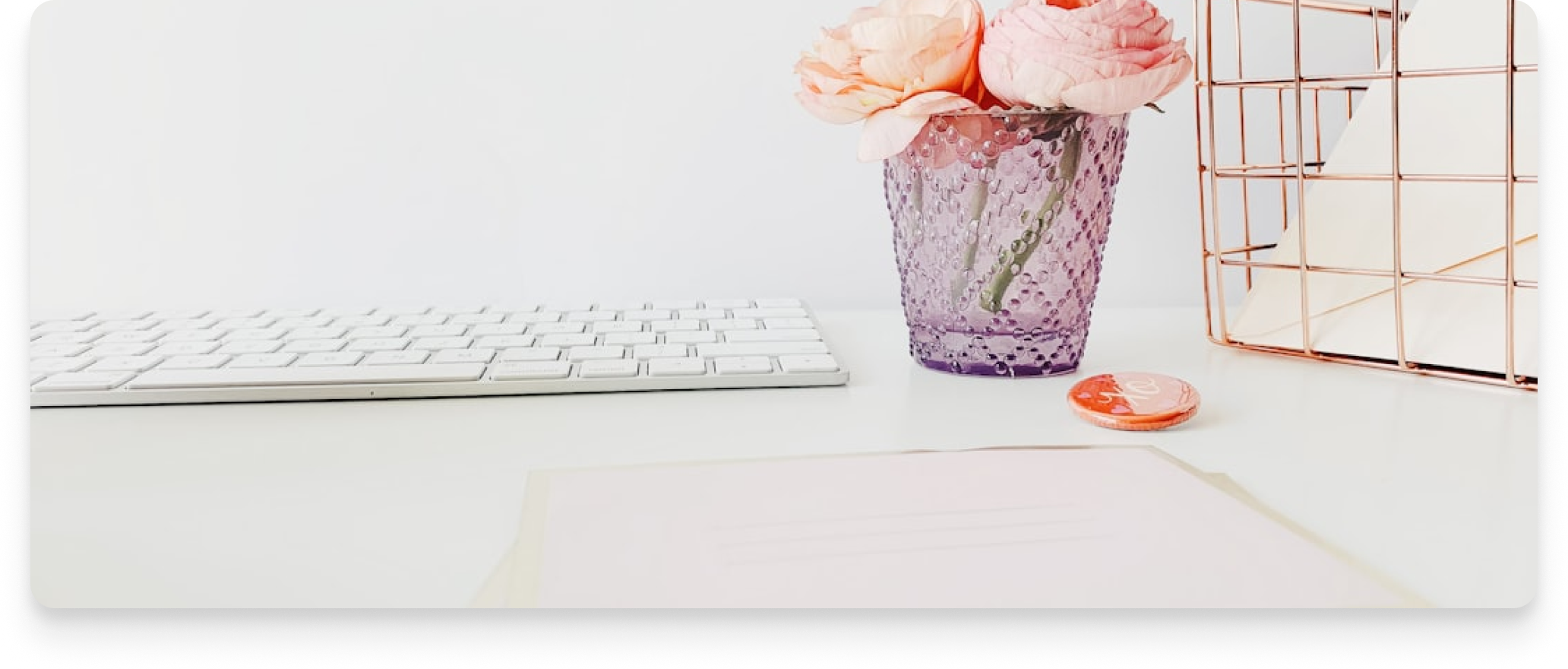 Workspace with peonies, keyboard, and a wire mesh panel